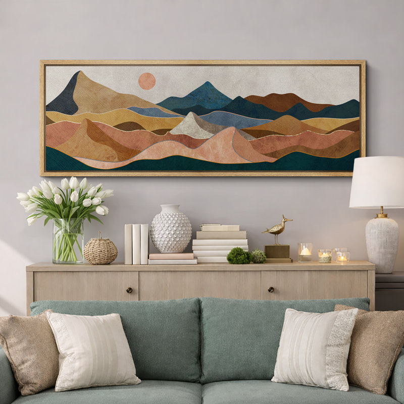 Panoramic framed wall art featuring an abstract desert mountain landscape in earthy tones of brown, blue, and tan.