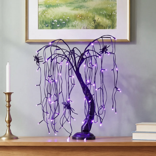 Lighted black willow tree Halloween decoration with purple LED lights and spider accents displayed on a mantle.