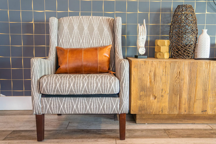 gray abstract-print arm chair with a cognac leather lumbar pillow