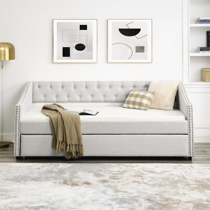 Lit de jour simple avec lit gigogne, rembourré en beige, dossier et accoudoirs cloutés en cuivre, revêtement en bouton beige