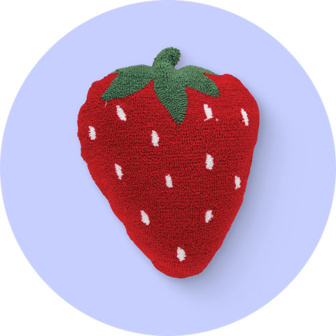 Un coussin décoratif en forme de fraise rouge avec des détails de tige verte sur un fond circulaire violet.