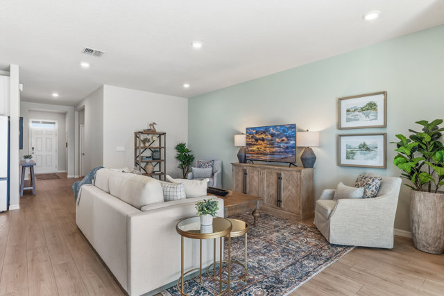 A living room with hardwood floors, a printed rug, and mint walls.