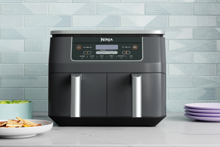 dark gray air fryer in front of a light blue backsplash