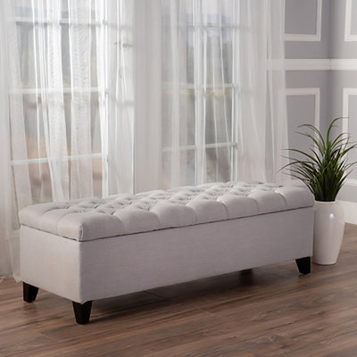 Repose-pieds de rangement contemporain avec capitonnage à boutons profonds et coutures en losange, idéal pour une utilisation polyvalente dans n'importe quel décor