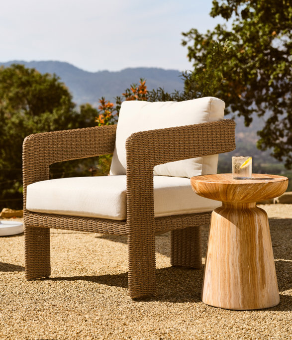 Wicker chair next to a wooden side table outdoors.