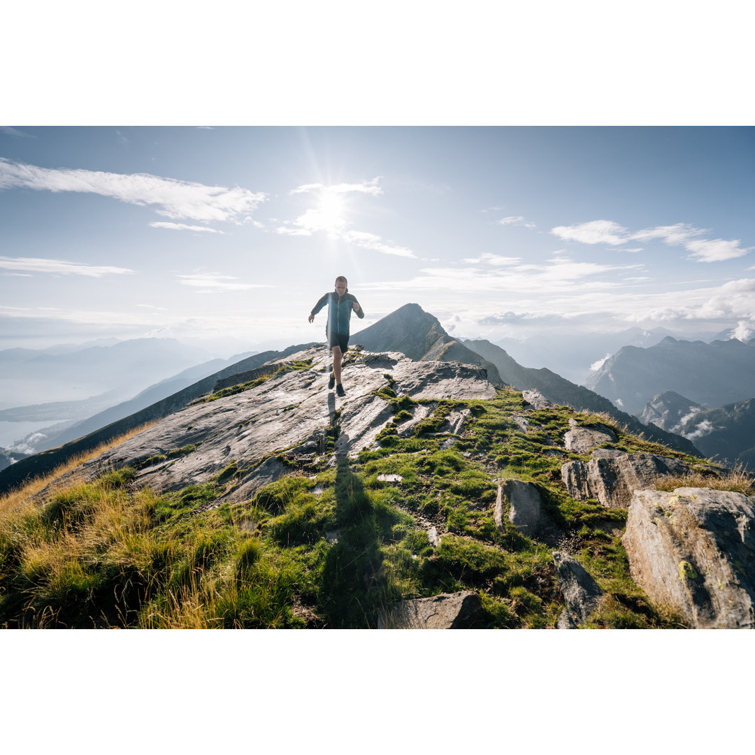 Trail Runner Bounds entlang eines Bergkamms ins Licht von AscentXmedia - Drucken