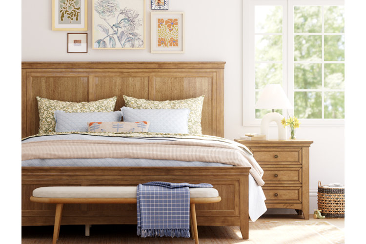 Budget-friendly bedroom decor with wooden bed frame, layered bedding, wall art gallery, and cozy neutral styling
