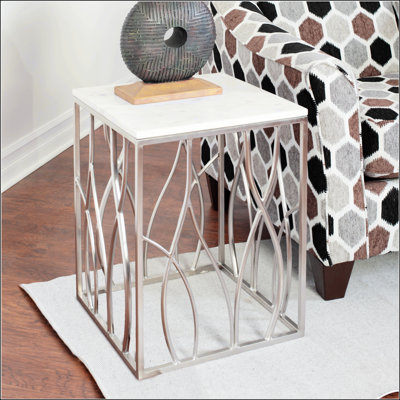 Table de bout carrée en marbre Kameral avec base en acier inoxydable, veines minérales uniques et courbes organiques pour une élégance moderne.