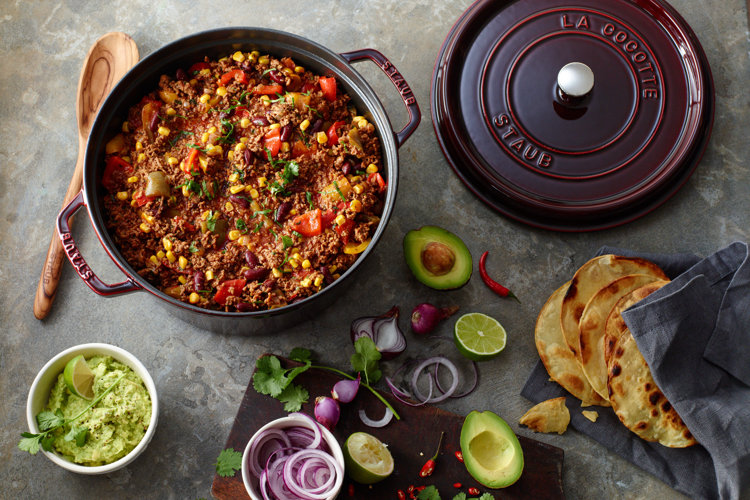 deep red casserole dish open and showing a delicious looking chili