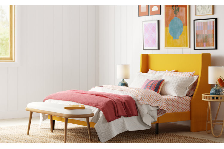bright boho bedroom with a yellow bed, patterned sheets, and a white quilt