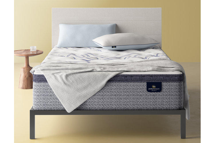 metal bed frame with a mattress, white upholstered headboard, and a wood nightstand