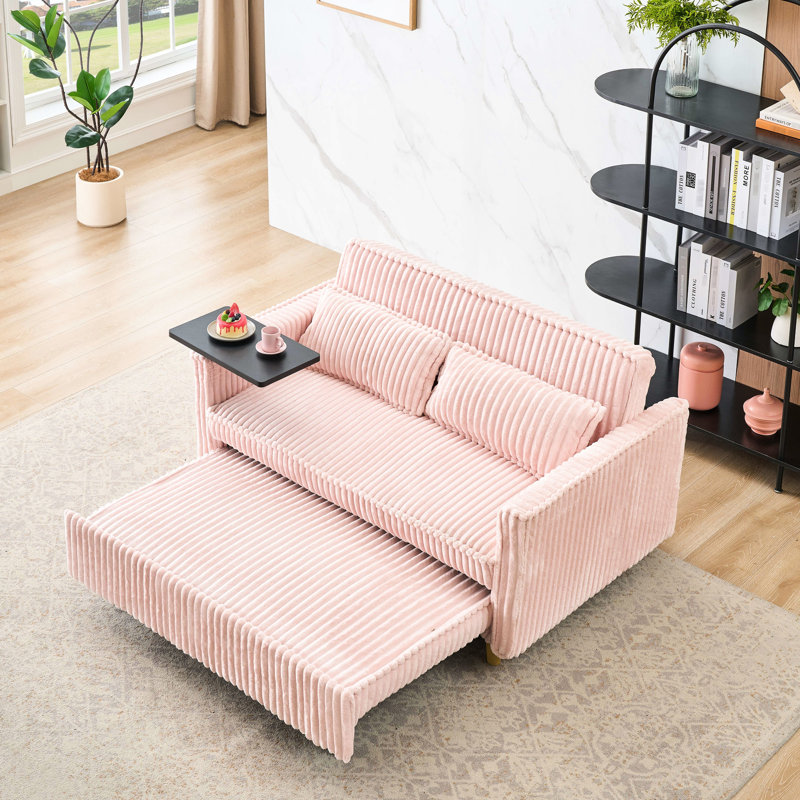 Velours côtelé rose avec des ajouts novateurs : lit gigogne, table basse amovible, ports pour une expérience inédite. Élégant : ports, se transforme en lit luxueux.