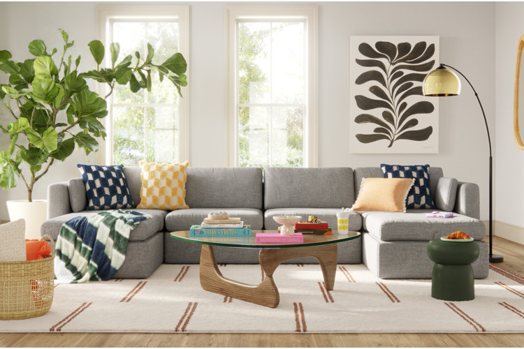 bright living room with a gray sectional, white sofa, wood-and-glass coffee table, and abstract piece of wall art