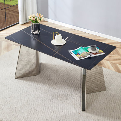 Table de salle à manger noire en marbre à motif de dalles avec pieds papillon en acier inoxydable. Le plateau de table est conçu pour résister aux égratignures et à la chaleur.