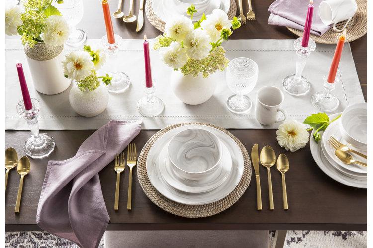 Dining room table with white table runner lavender napkins and white and gold table settings