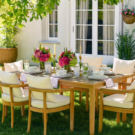 Outdoor dining table set with floral pattern dishware and centerpieces.