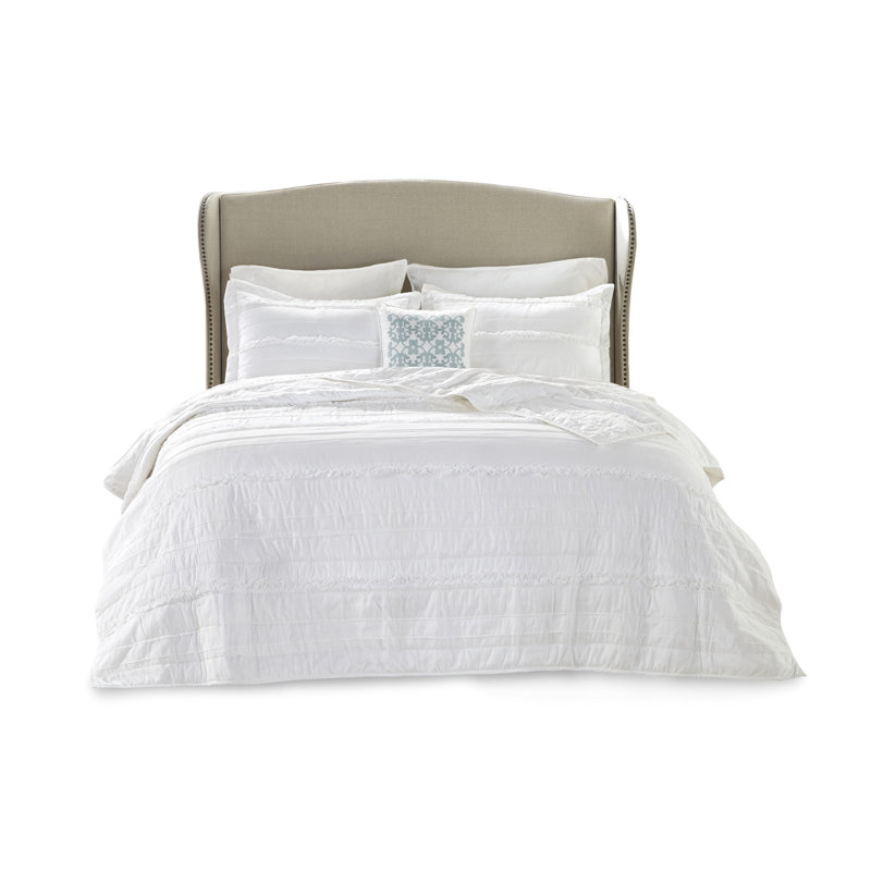 Literie blanche avec des détails de volants moelleux et un oreiller - la chaleur de la chambre à coucher