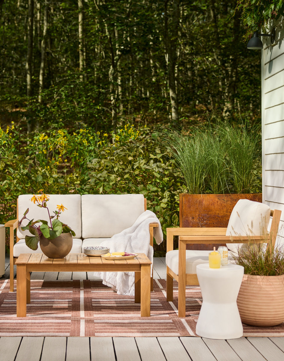 Outdoor seating area with a love seat, chair, area rug, and side table.