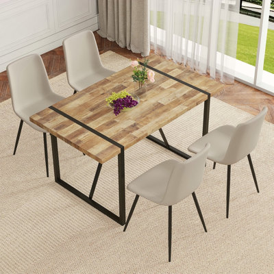 Ensemble de table et de chaises.Une table de salle à manger rectangulaire rétro minimaliste avec un plateau texturé et des pieds en métal noir. Elle est accompagnée de 4 chaises en polyuréthane artificiel gris clair chaud avec un design de coussin i