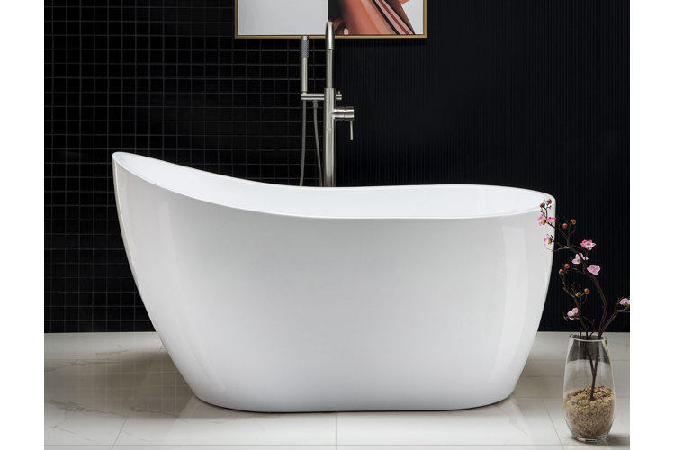 A white acrylic slipper tub on white marble floors and in front of a black tiled accent wall.