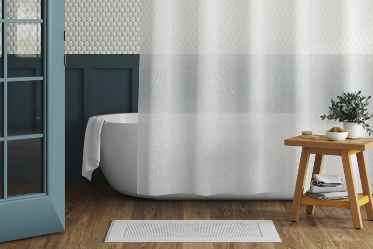 white soaking tub with a sheer white shower curtain, white bath mat, and a wood shower stool