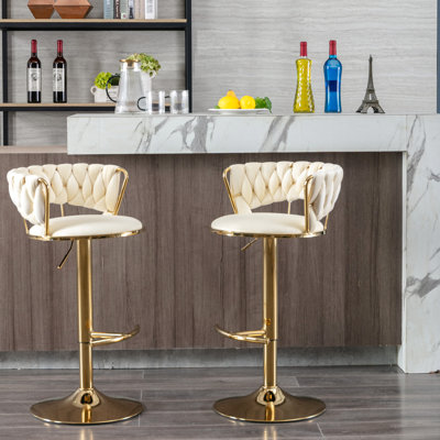 Deux tabourets de bar, velours crème, pieds dorés, repose-pieds et base, réglables en hauteur par 2 leviers mécaniques recouverts de tissu, et pivotant en hauteur