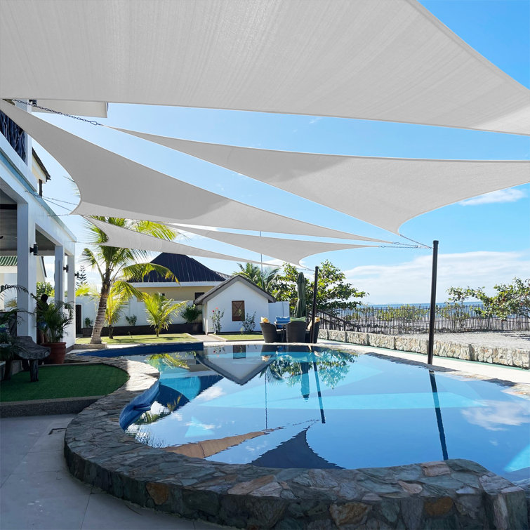 Suspended white triangular shades above an inground pool with ocean view