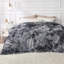 Shaggy faux fur blanket in grey and white draped over a bed