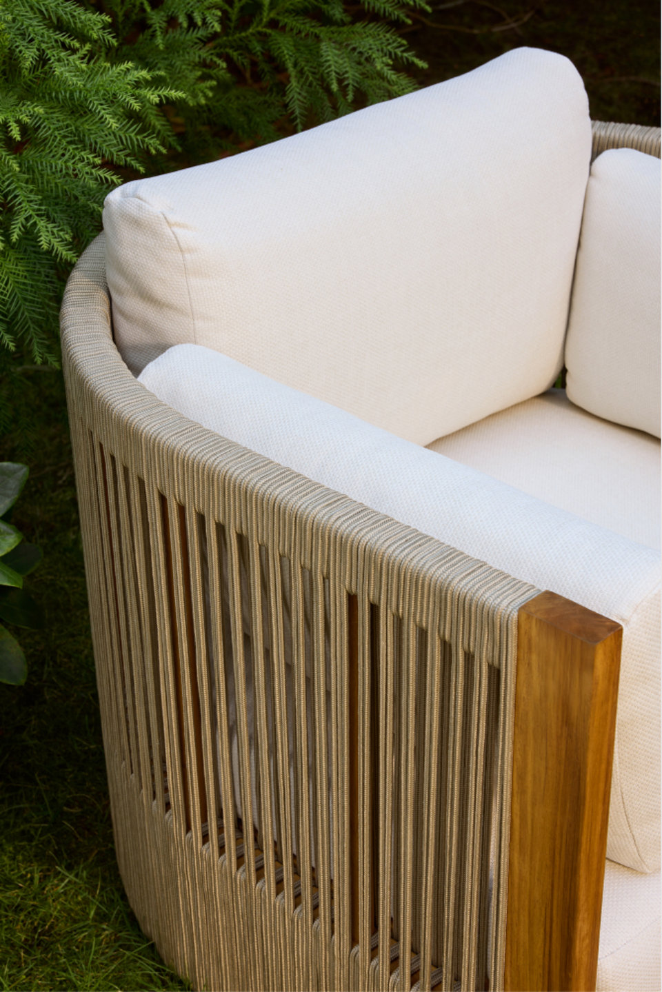 Close-up of an outdoor sofa with beige cushions and rope back.