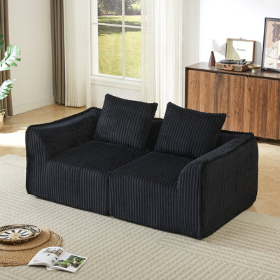 Canapé minimaliste en velours côtelé aux lignes courbes et au dossier légèrement incliné, livré avec deux coussins décoratifs, un coussin décoratif en forme de corne noir