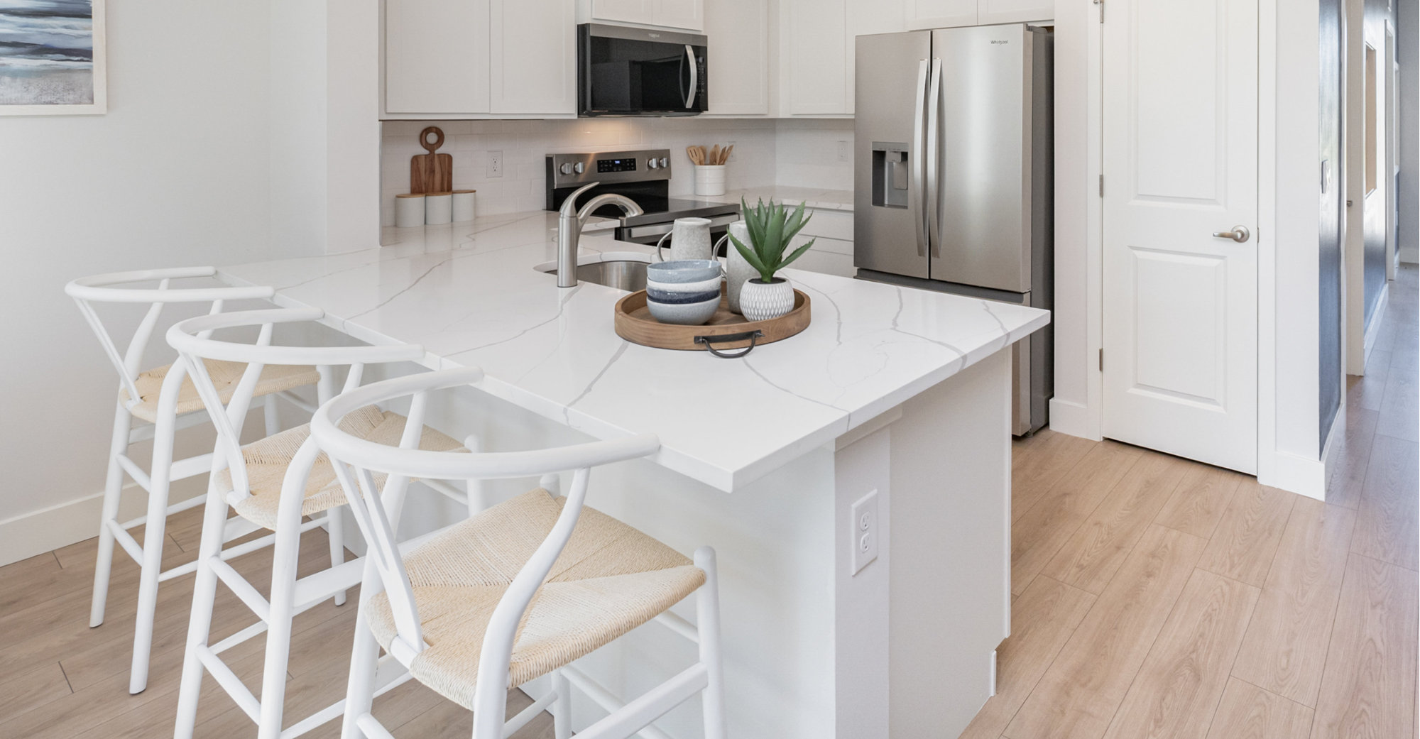 Kitchen with white marble countertop and white bar stools.