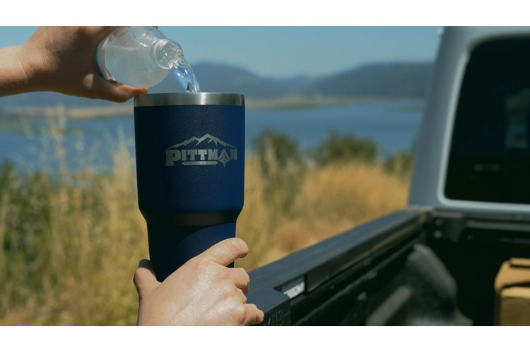 an insulated travel tumbler with water being poured into it