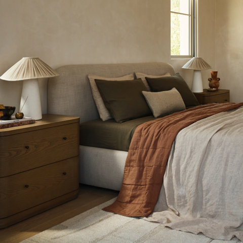 Bedroom with lamps on nightstands, a bed with brown and beige bedding, and a neutral rug.