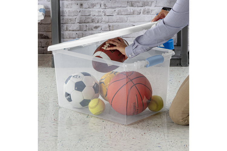 Someone putting sports balls into a clear storage container