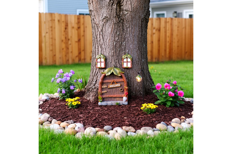 resin fairy garden accessories around the base of a tree trunk