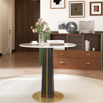 Table ronde moderne avec un plateau en pierre frittée de 85 cm, des pieds en bois noir et un support en métal doré, idéal pour les discussions de salle à manger sur une base en bois blanc, un choix pratique