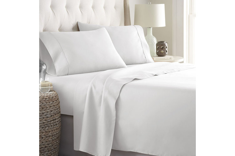 Upholstered bed with white bed sheets and pillowcases.