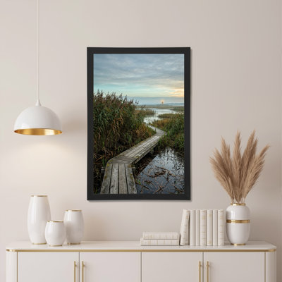 Toile en bois à travers les herbes du marais avec phare lointain