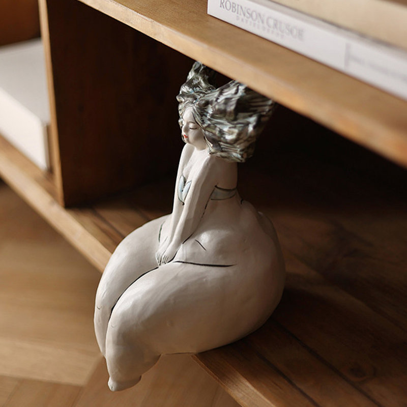 Objet décoratif en céramique représentant une femme assise aux courbes blanches