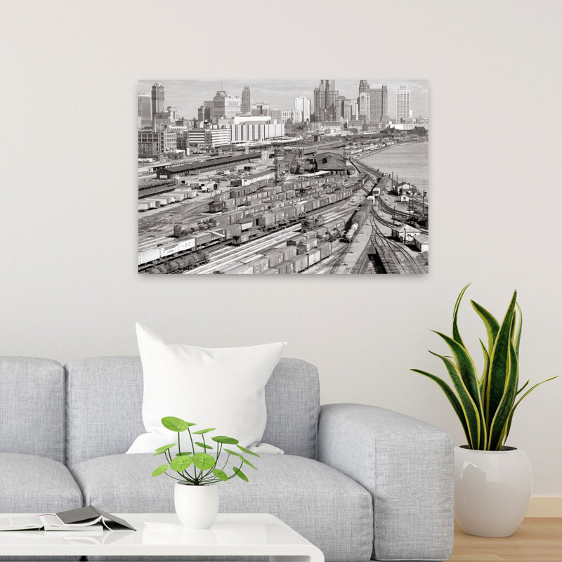 1960s INDUSTRIAL FREIGHT TRUCKING AND RAILROAD BOXCAR TRAIN YARDS ALONG RIVER CITY BUILDINGS SKYLINE IN B G DETROIT MICHIGAN USA by H. Armstrong Roberts - Wrapped Canvas Print