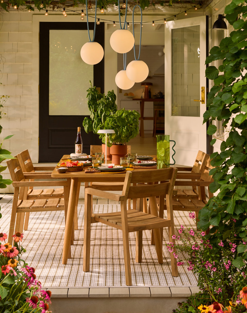 Outdoor dining table with chairs and globe pendant lights.