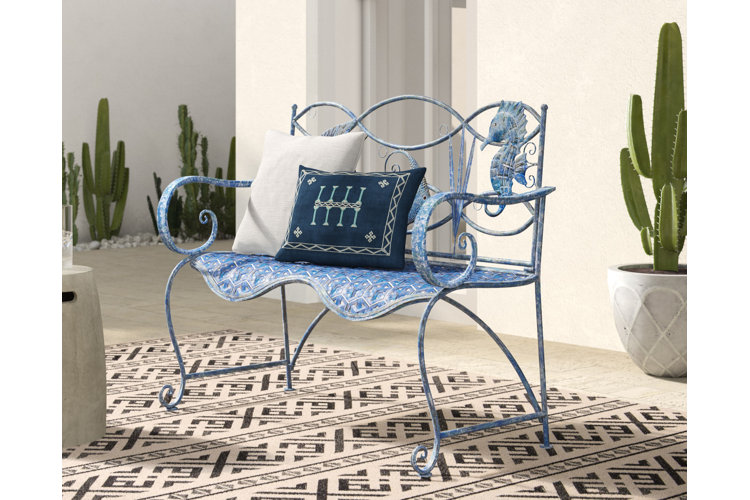 blue outdoor metal bench with underwater artwork design on the back. Blue and white outdoor throw pillows and various cacti dotted around