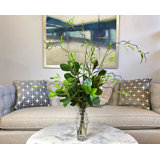 Arrangement de branches de saule dans un grand vase en verre avec feuillage