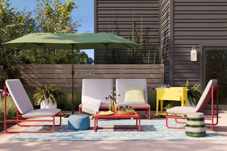 yellow patio cooler beside a red metal patio conversation set, green patio umbrella, and a blue outdoor rug