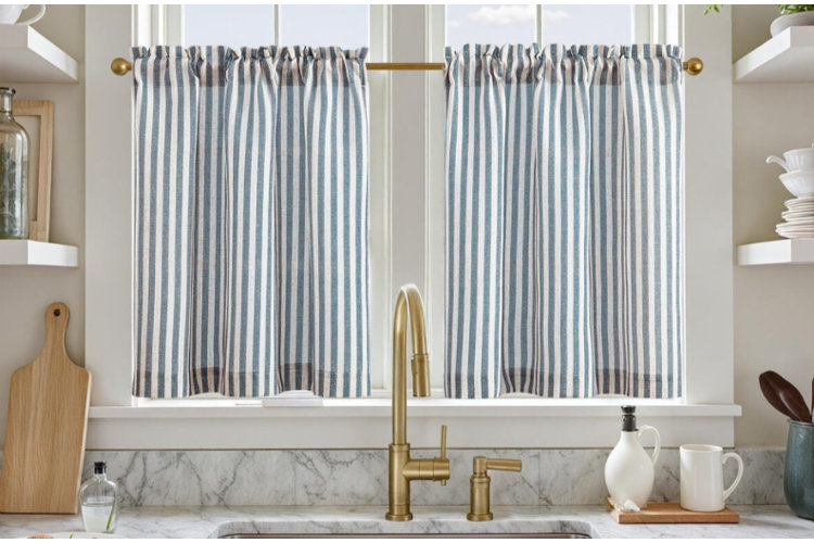 striped cafe curtains with gold fixtures hanging above marble backsplash