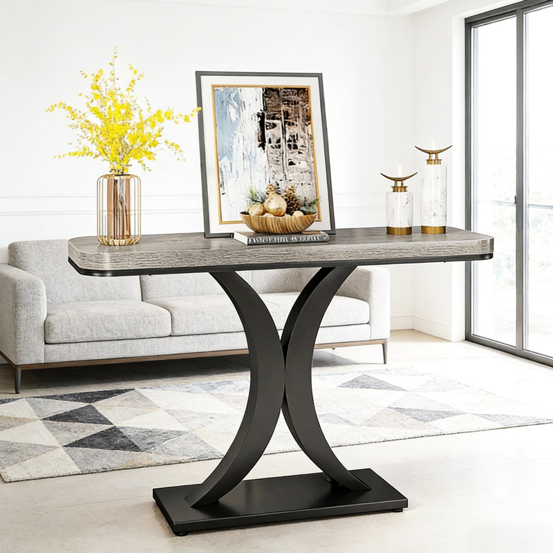 Table d'entrée de style industriel moderne, console compacte avec piètement en bois épais et incurvé, idéale pour le salon, le bureau ou le couloir. Longueur : 100 cm (39,4 po). Plateau design et lignes géométriques allongées.