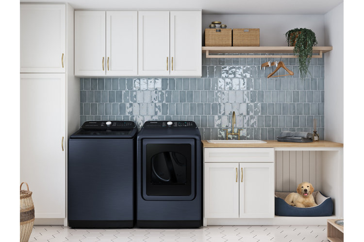 kitchen laundry area with washing machine and tumbler dryer next to a dog bed with a puppy in it