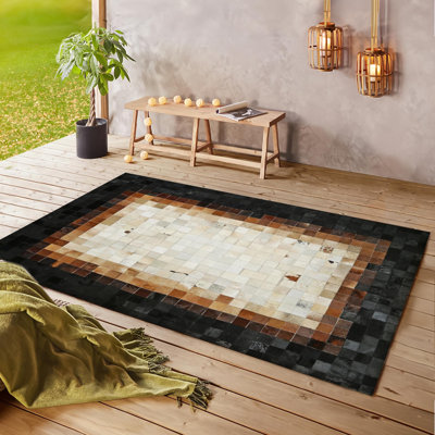 Tapis brun et beige en peau de vache avec bordure noire