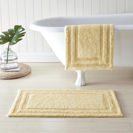 Beige bath mats next to a tub.
