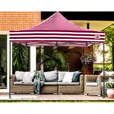 Pop-up canopy with red and white horizontal stripes set up over an outdoor wicker sofa set on a patio.